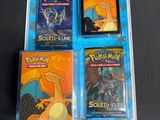 trois cartes à collectionner Pokémon dans un étui en plastique posé sur une table