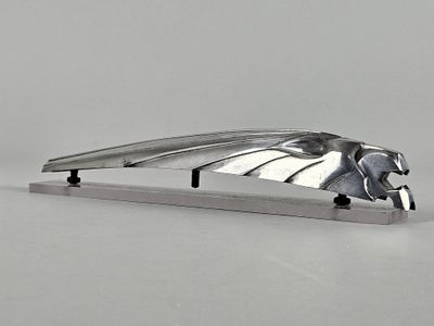 un objet en métal orné d'un oiseau, posé sur une table