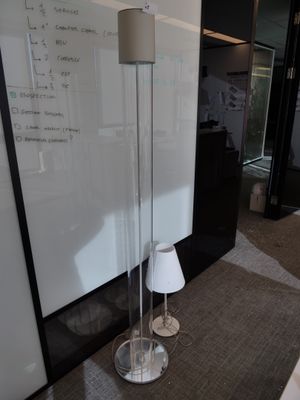 une lampe posée par terre devant un tableau blanc