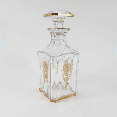 a clear glass bottle with a gold decoration on it