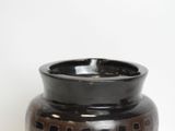 a black and brown vase sitting on a white surface