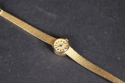 une image représentant une montre-bracelet en or posée sur une surface noire