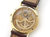 a gold watch with a brown leather strap on a white surface