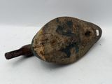an old rusty metal object with a wooden handle sitting on a white surface