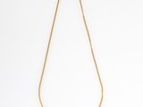 a gold necklace with a green bead on a chain