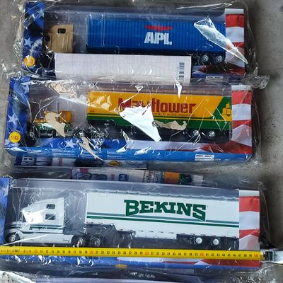trois petits trains jouets dans des sacs en plastique posés par terre