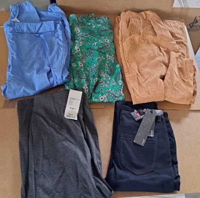 quatre paires de pantalons dans une boîte posée par terre