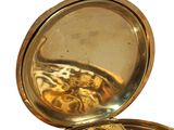 a gold pocket watch with gears in it on a white surface