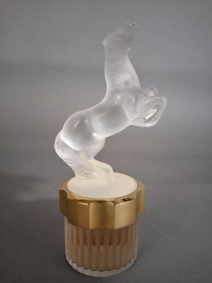 une figurine en verre représentant un cheval, posée sur un socle en bois