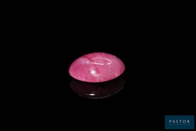 un gros plan d'une pierre rose sur une surface noire