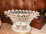 a white and gold bowl sitting on top of a wooden table