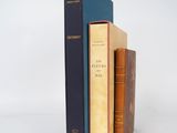 trois livres sont empilés sur une surface blanche