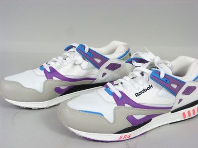 Des baskets violettes et blanches rehaussées de touches violettes reposent sur une surface blanche