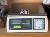 une photo d'une balance posée sur un bureau, à côté d'une calculatrice