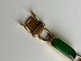 a bracelet with a green stone on it on a white surface
