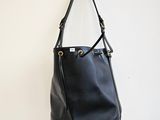 un sac à main en cuir noir accroché à un mur blanc