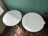 two marble tables sitting next to each other on a tiled floor