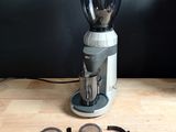 a coffee grinder sitting on a wooden table next to a cup of coffee