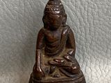 figurine de Bouddha assise sur une surface en cuir blanc, sur fond blanc