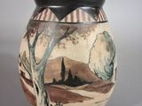 a vase with a painting on it sitting on a table