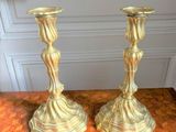two gold candlesticks sitting on a wooden table