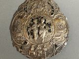 une broche ancienne en argent sur laquelle est représenté un homme et une femme