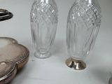two glass vases sitting on a table next to a plate