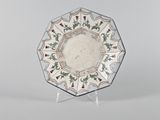 une image représentant une assiette décorative posée sur un socle, sur fond blanc