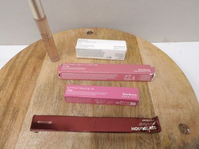 trois gloss posés sur une table en bois, à côté d'une boîte de baume à lèvres