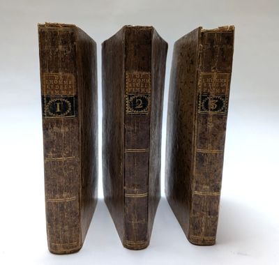 trois vieux livres posés l'un sur l'autre sur une surface blanche