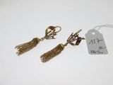 une paire de boucles d'oreilles dorées ornées de pompons, avec son étiquette de prix