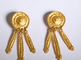 paire de boucles d'oreilles dorées ornées de pompons sur fond blanc