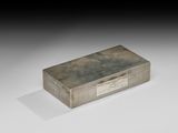 une vieille boîte en argent munie d'une poignée, posée sur une surface blanche