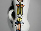 un vase blanc orné d'un motif, accroché au mur