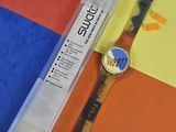 une montre et un stylo posés sur une surface colorée