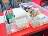 a red table with plastic containers on it in a classroom