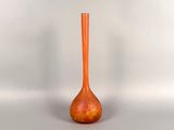 a small orange vase sitting on a white surface