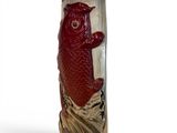 a red vase with a fish on it on a white surface