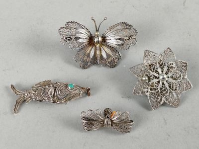 three silver brooches with a butterfly, fish, and a fish on them