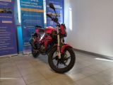 une moto rouge garée devant un panneau bleu et blanc