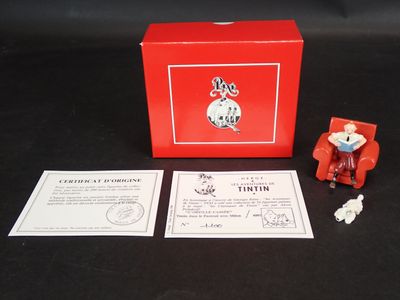 une boîte rouge contenant une petite figurine représentant un homme assis sur une chaise rouge