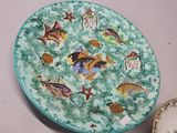une assiette ornée d'un motif de poisson à côté d'une assiette ornée d'un motif de poisson