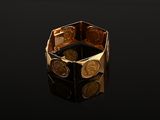 an image of a gold ring with coins on a black surface