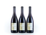 three bottles of wine are lined up on a white surface
