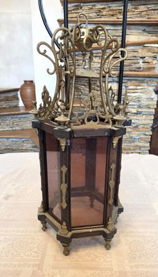une petite lanterne posée sur une table, avec un mur de pierre en arrière-plan