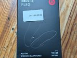 La boîte des écouteurs Beats Flexx est posée sur une table en bois.