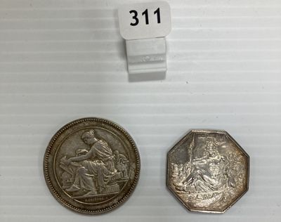 deux pièces d'argent posées l'une à côté de l'autre sur une surface blanche