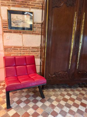 a red chair sitting in front of a wooden armoire