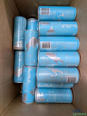 several cans of canned food in a cardboard box on a table