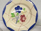 a plate with a flower painted on it next to a plate with a flower painted on it